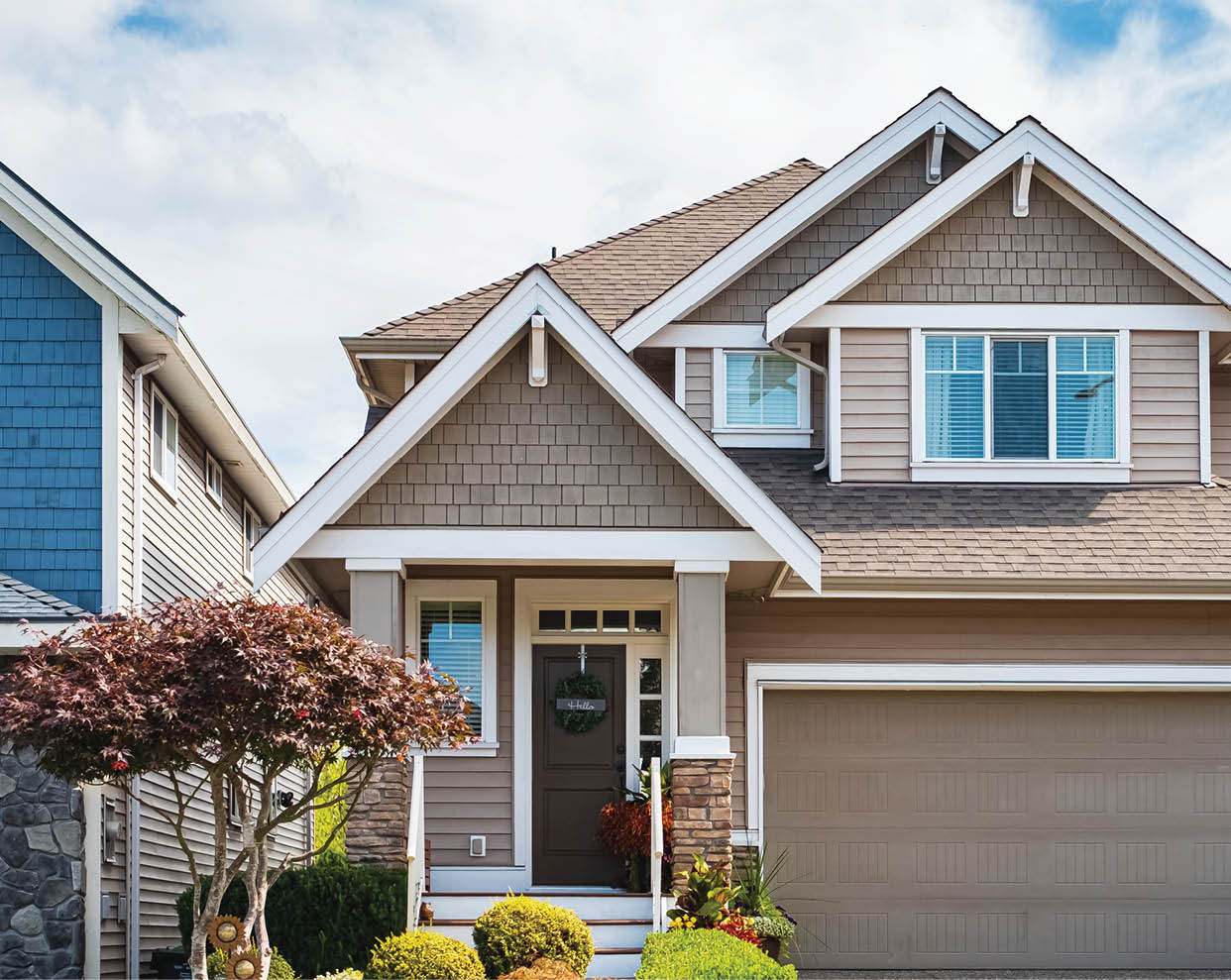 Real Estate Exterior Front House on a sunny day. Big custom made luxury house with nicely landscaped front yard and driveway to garage in suburbs. Modern designed home, New construction home exterior